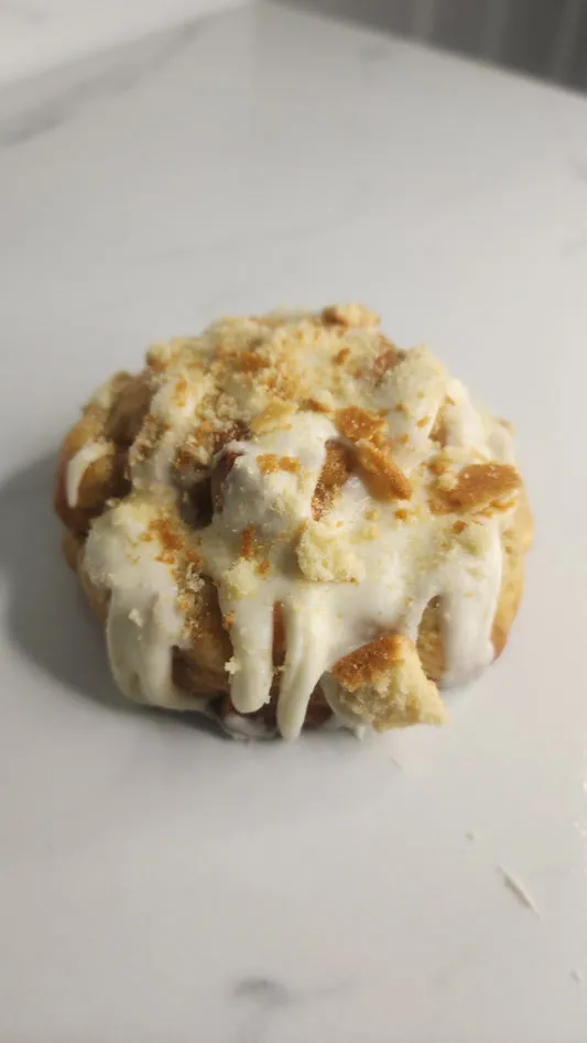 Banana pudding cookie topped with creamy white icing and cookie crumbs