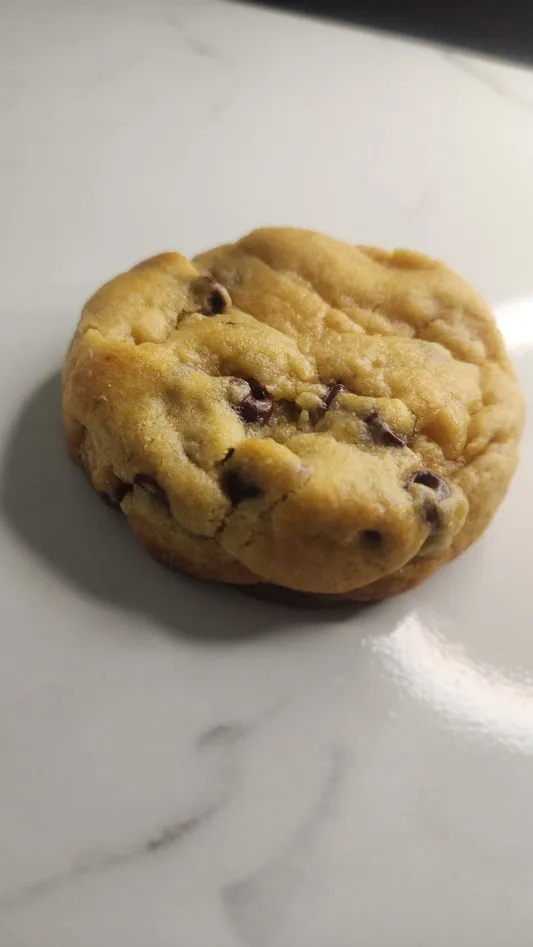 Golden chocolate chip cookie on a marble surface
