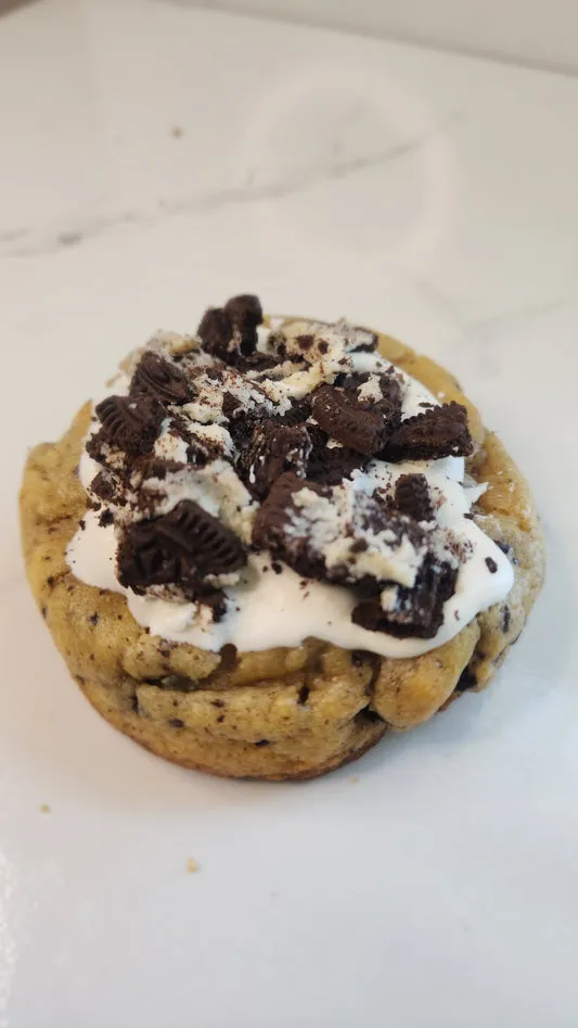 Cookies and cream cookie topped with white icing and chocolate cookie pieces