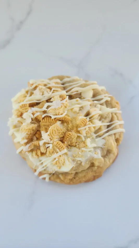 Golden cookies and cream cookie topped with vanilla drizzle and golden crumbs