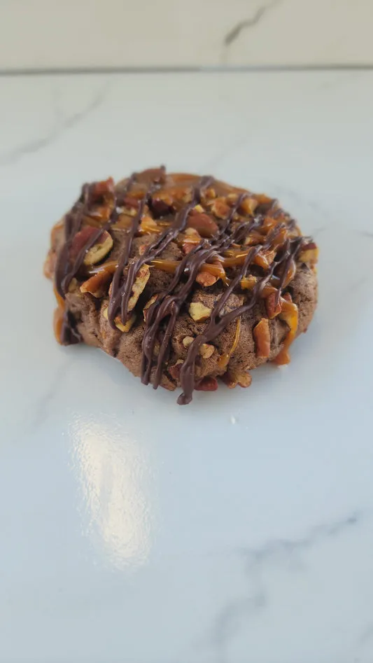 Chocolate turtle cookie topped with pecans, caramel, and chocolate drizzle